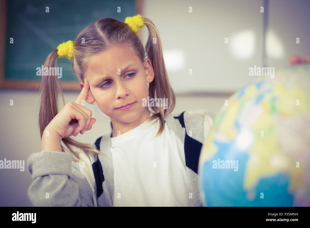 Concentrated pupil looking at globe in a classroom Stock Photo - Alamy