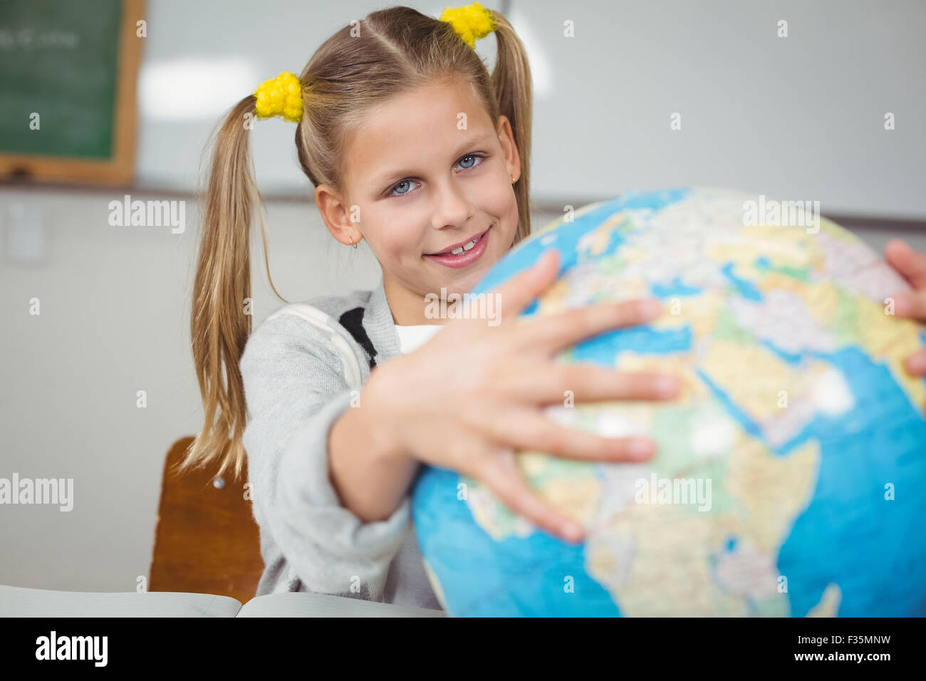Cute pupil holding globe in a classroom Stock Photo - Alamy