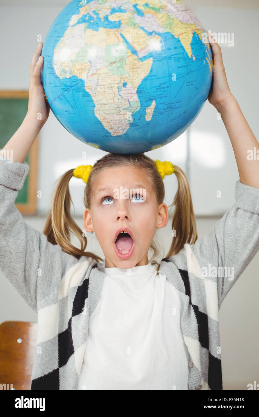 Cute pupil balancing globe on head in a classroom Stock Photo - Alamy