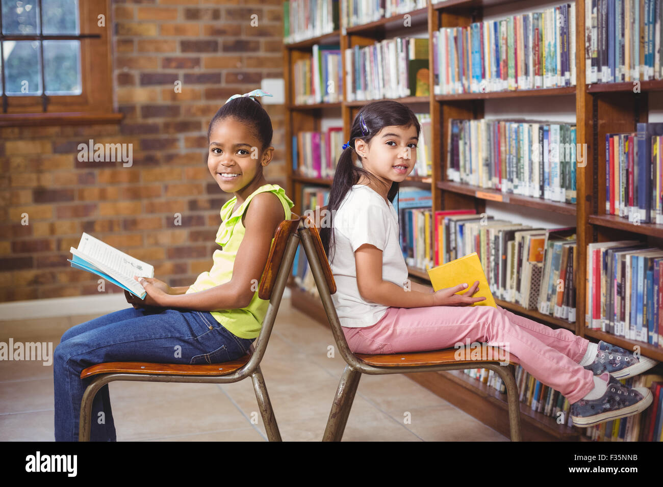 Smiling pupils reading books in the library Stock Photo - Alamy
