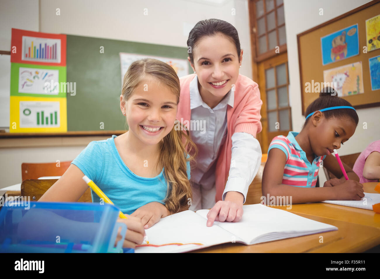 Pupil and teacher smiling at camera during class Stock Photo - Alamy