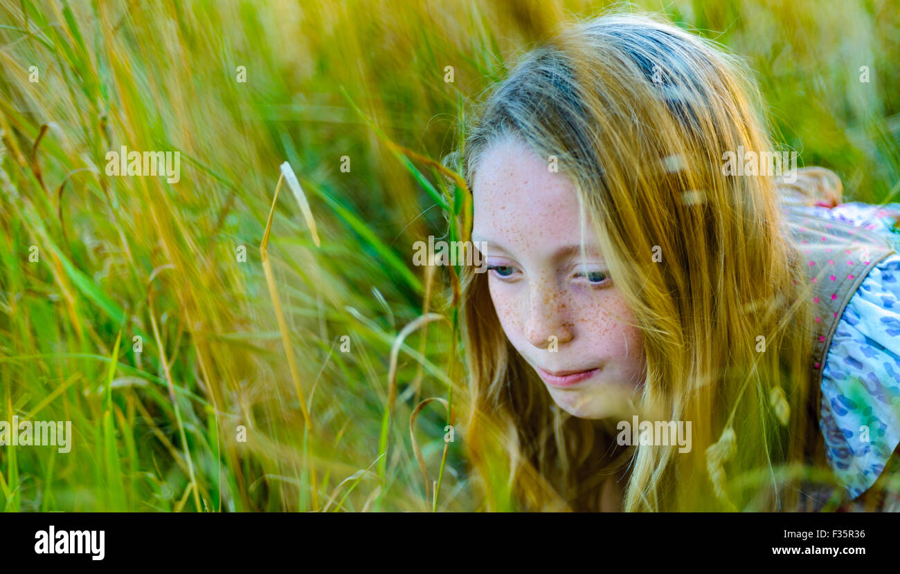 Portrait of an eight year old girl in a field of long grass at sunset on a summers evening Stock Photo