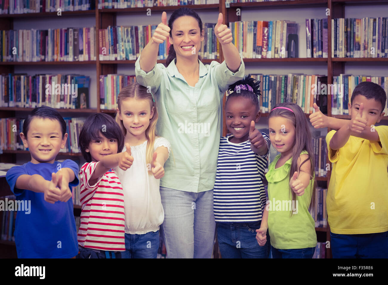 Pupils and teacher smiling at camera in library Stock Photo - Alamy