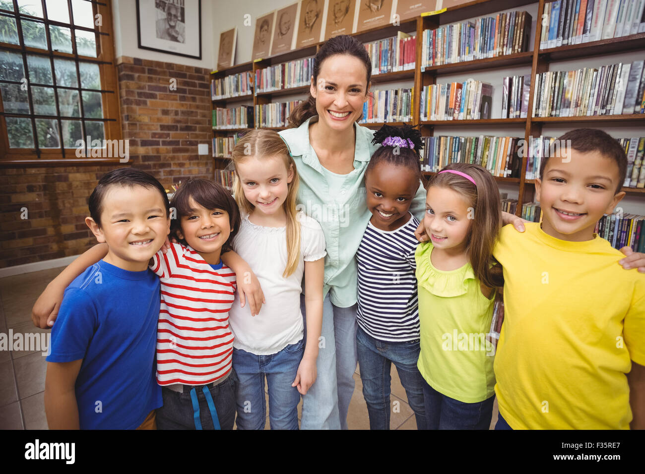 Pupils and teacher smiling at camera in library Stock Photo - Alamy