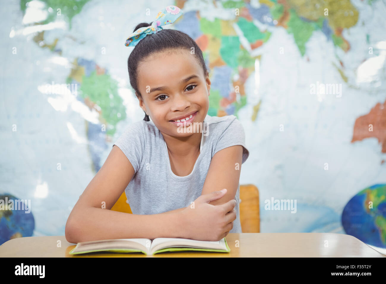 Smiling student with a book on the desk Stock Photo - Alamy