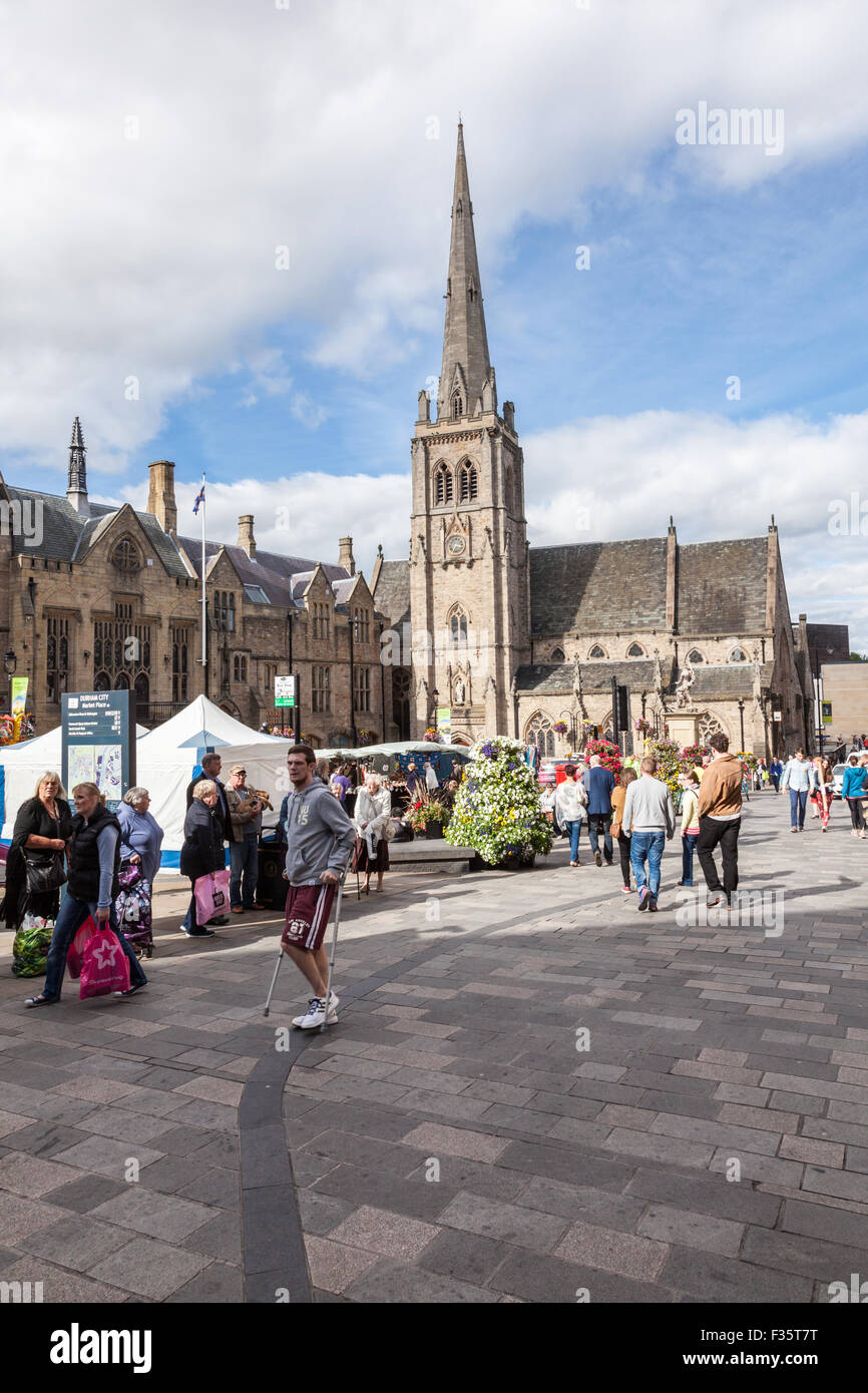 Man wih crutches crosses the busy Market Square in Durham city center, Durham, UK Stock Photo