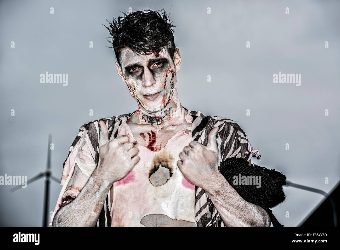 One male zombie standing in empty city street at night looking at camera. Halloween theme Stock Photo