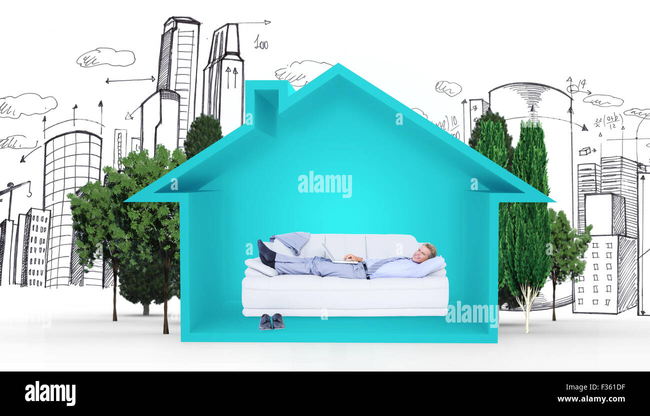 Composite image of  businessman lying on sofa using his laptop smiling at camera Stock Photo