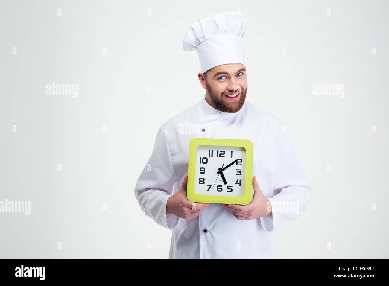 Portrait of a happy male chef cook holding wall clock isolated on a white background Stock Photo