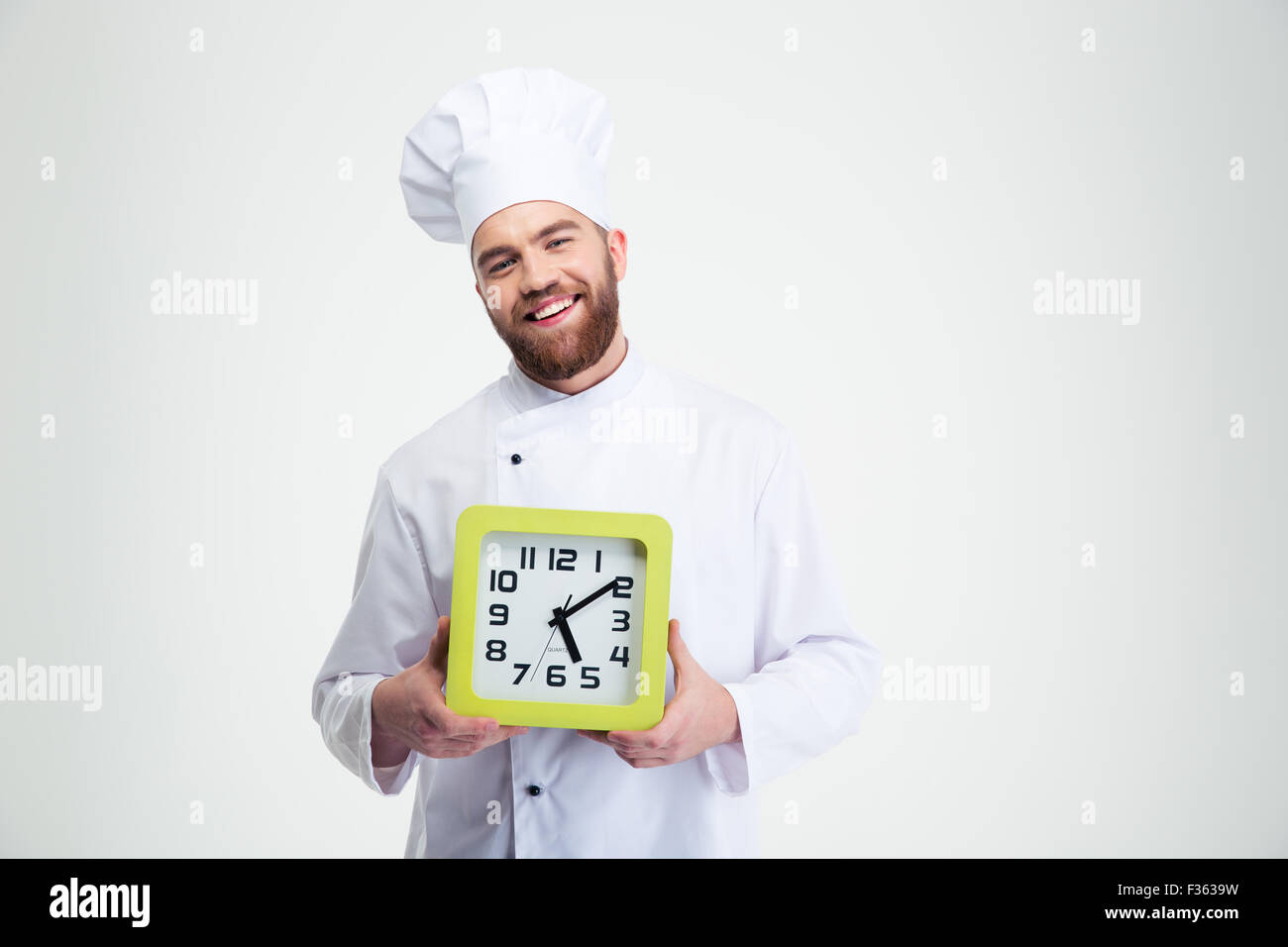 Portrait of a laughing male chef cook holding wall clock isolated on a white background Stock Photo
