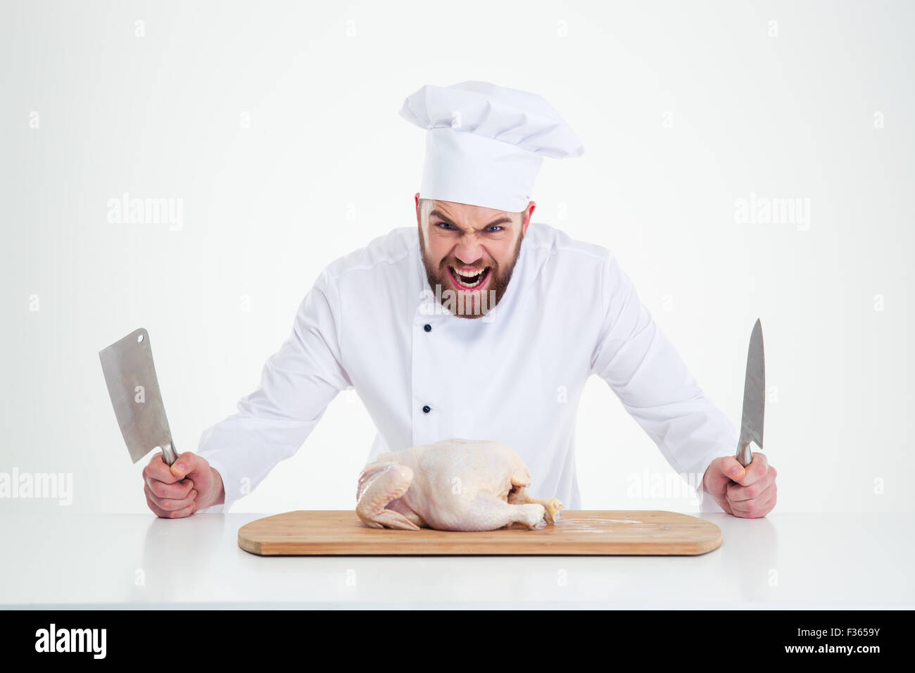 Portrait of angry male chef cook standing with knifes and chicken on