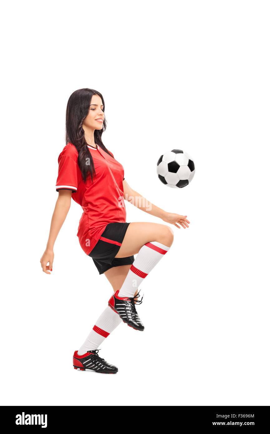 Full length profile shot of a female soccer player juggling a ball on her knee isolated on white background Stock Photo