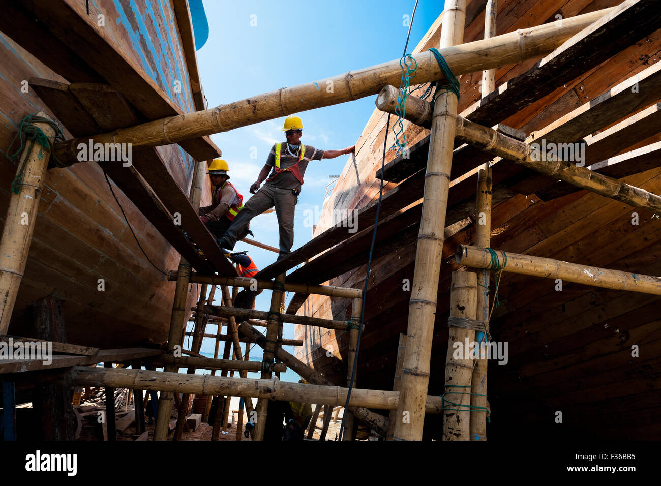Ecuadorian shipbuilding workers provide maintenance to the traditional wooden fishing vessels in a shipyard in Manta, Ecuador. Stock Photo