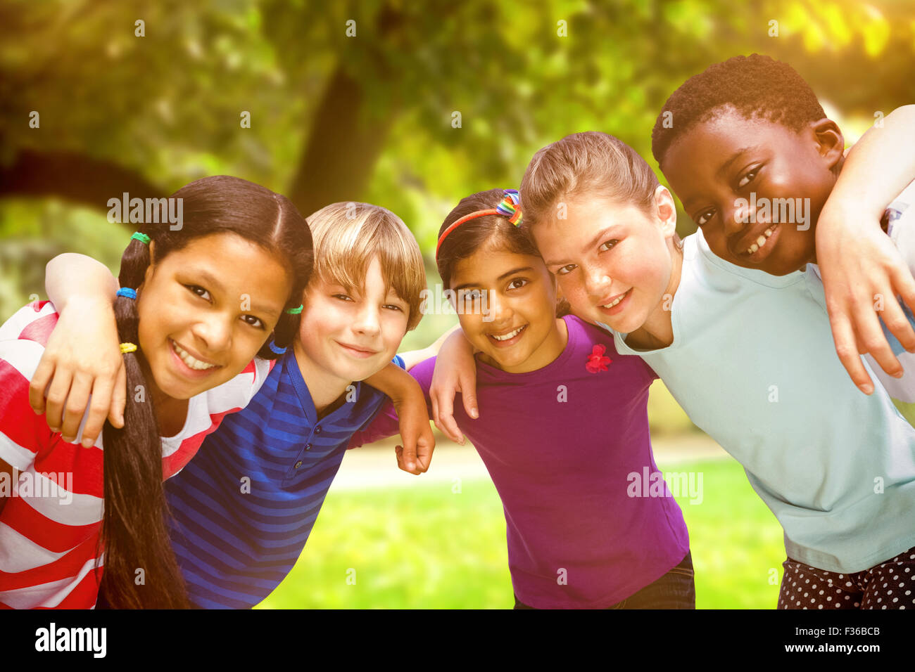 Composite image of happy children forming huddle at park Stock Photo