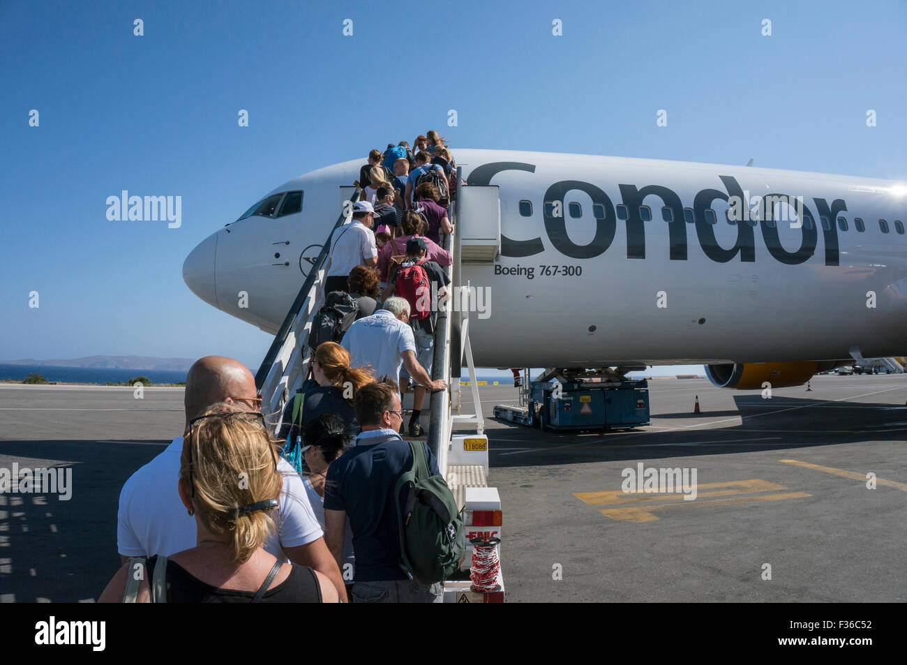 An aircraft of the airline Condor at the airport Heraklion in Crete. Passengers just boarding the plane over a gangway. Stock Photo