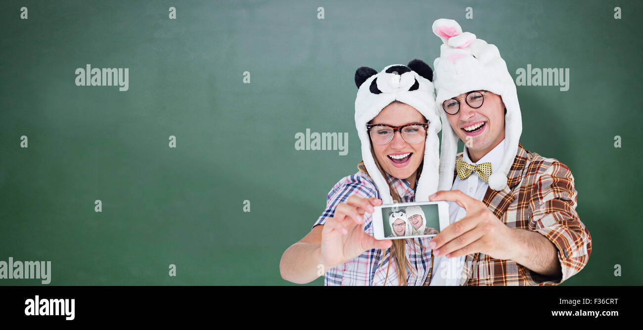 Composite image of geeky hipster couple taking selfie with smart phone Stock Photo