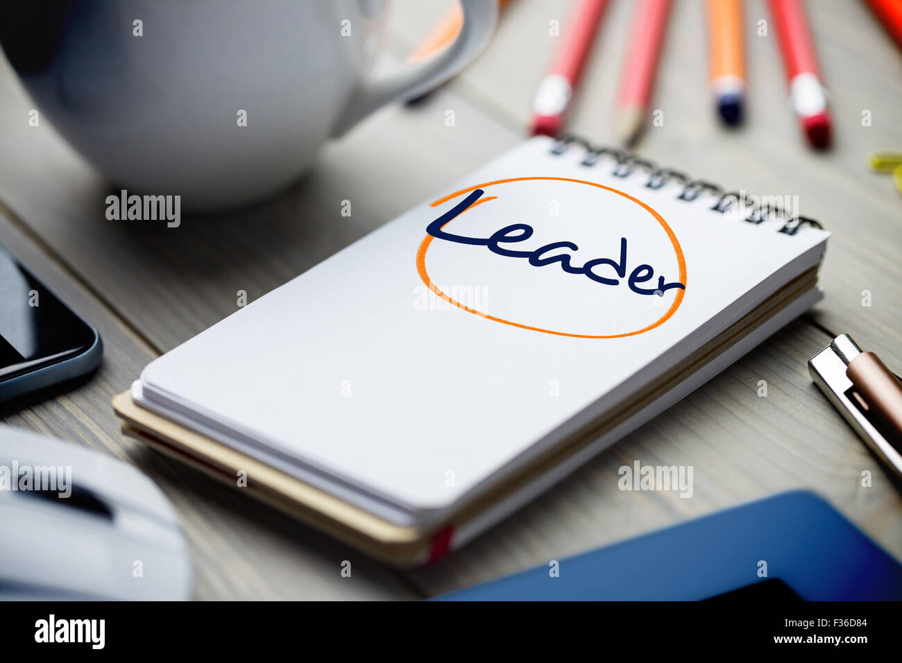 Leader against notepad on desk Stock Photo - Alamy