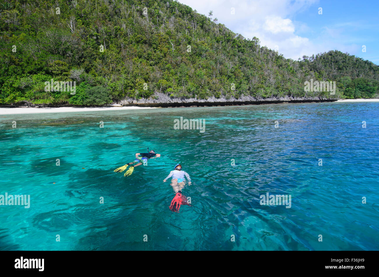 Two snorkelers exploring the lagoon and reefs of Wayag island group ...