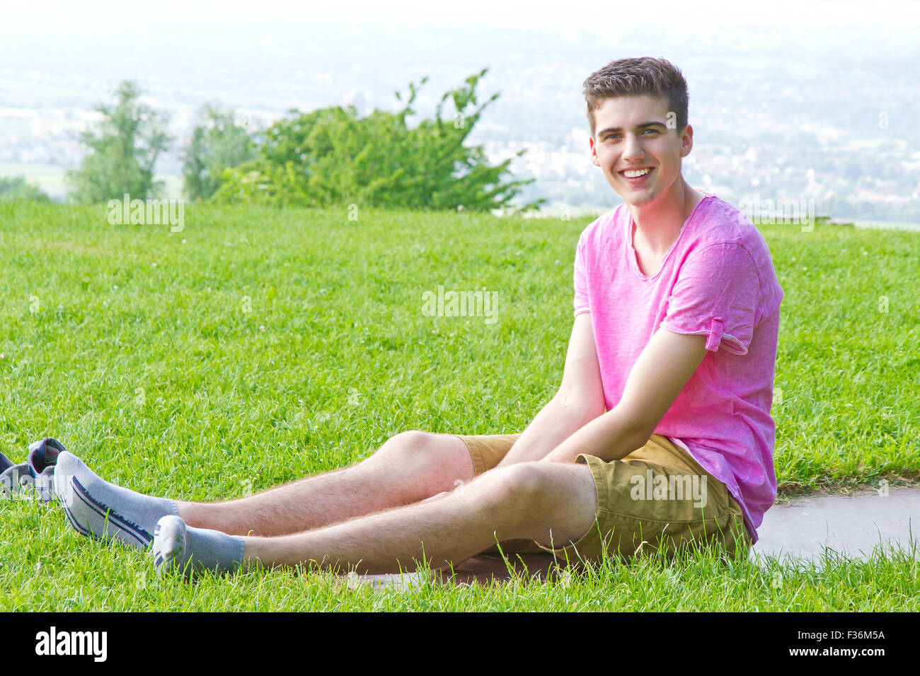 Young, happy man sitting on a meadow Stock Photo