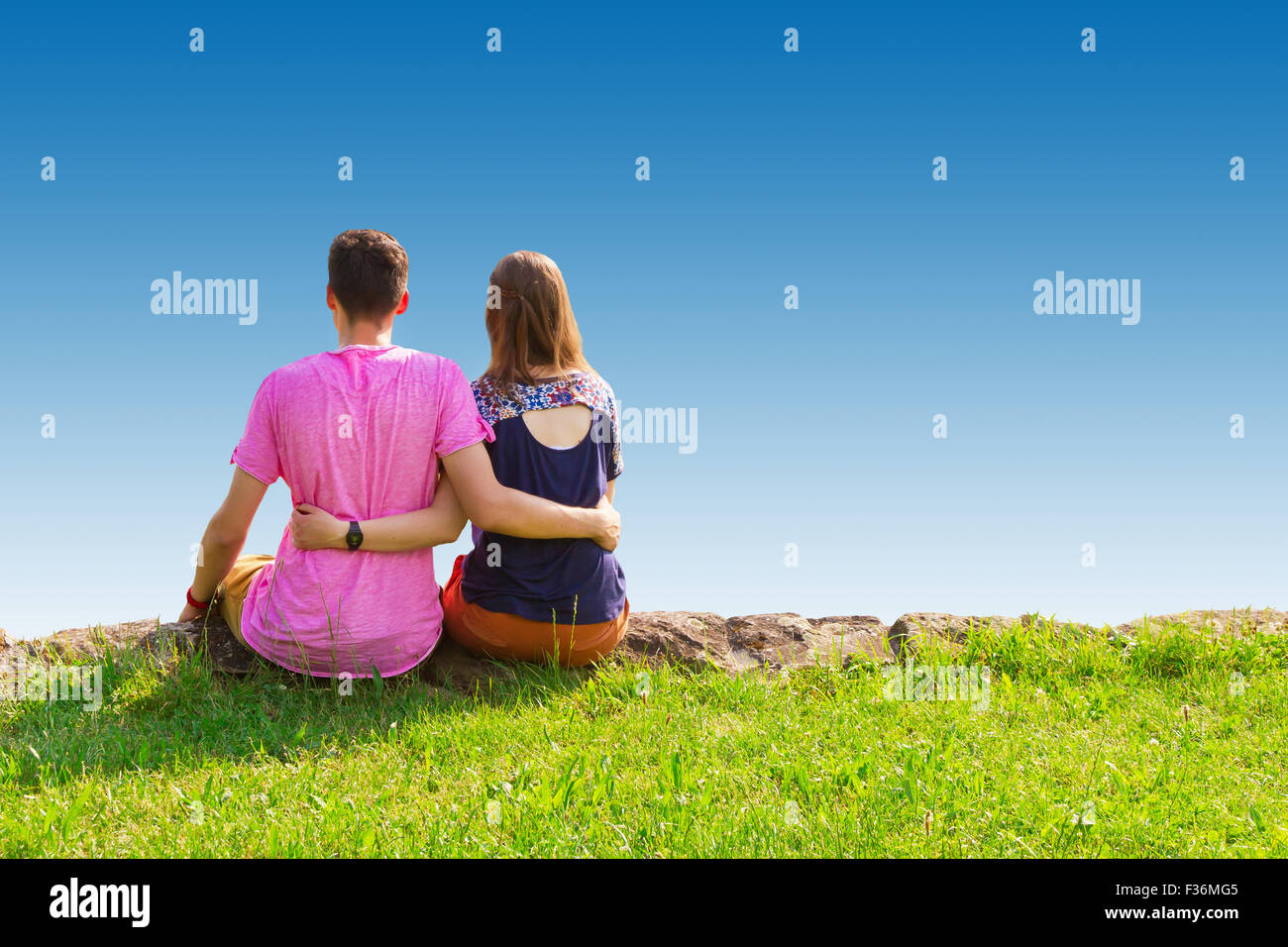 Young love couple sitting on a green meadow Stock Photo