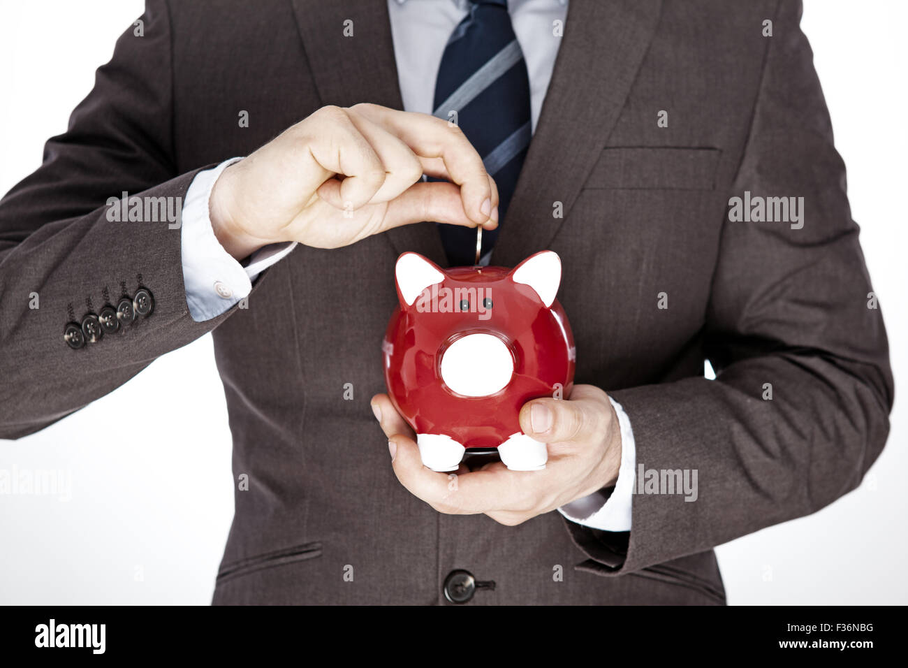 Male hand putting coin into a piggy bank Stock Photo - Alamy