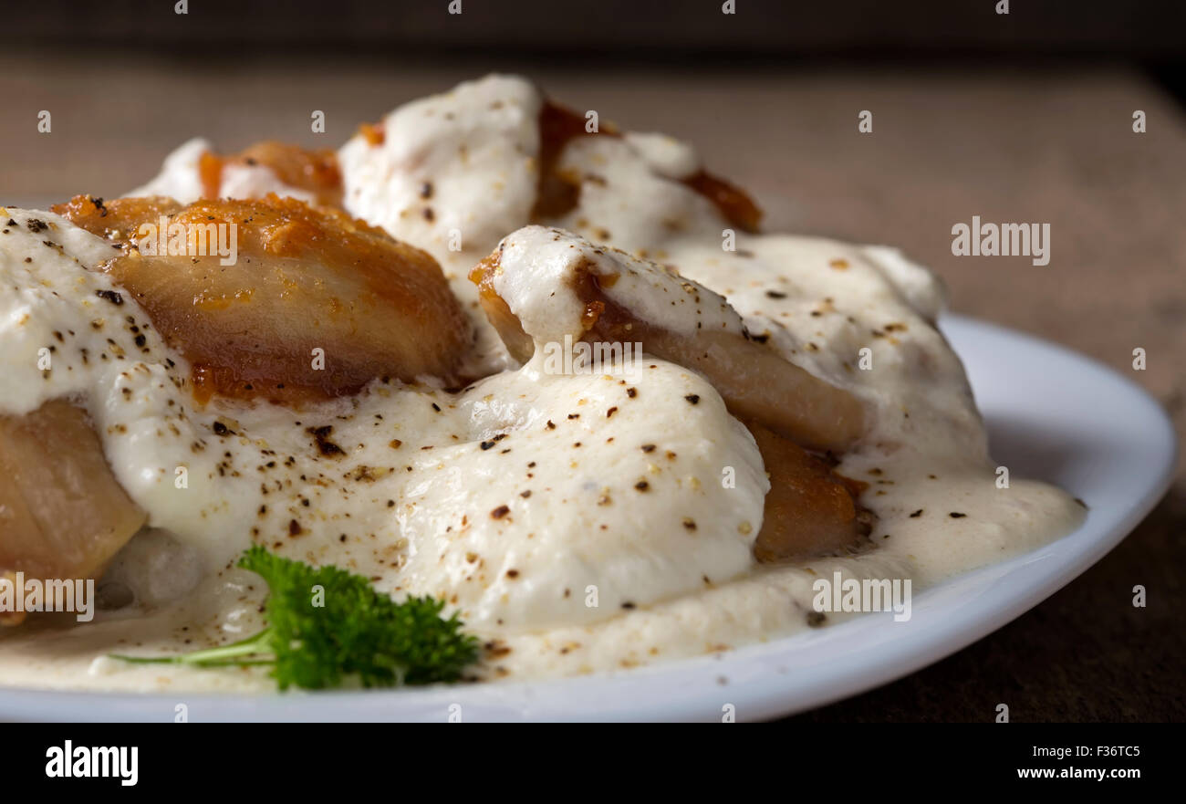 Chicken with sour cream on white plate over wooden rustic background Stock Photo