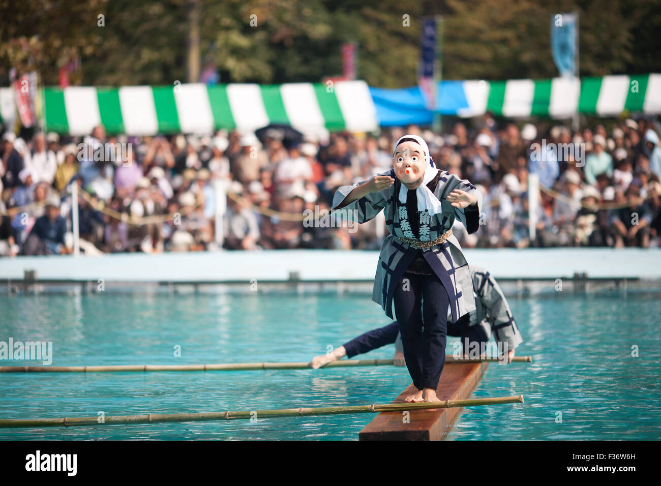 Performer wearing mask traditional Japanese yukata balancing on square log on water Stock Photo