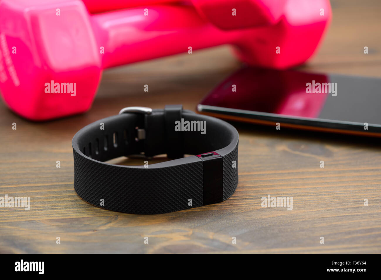 wearable device, wirst watch type Sports tracker with smartphone and pink colored dumb-bell on a wooden board Stock Photo