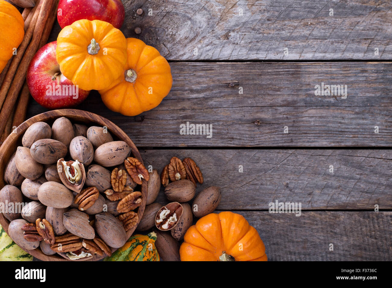 Pumpkins, nuts, indian corn and apples on a rustic table overhead ...