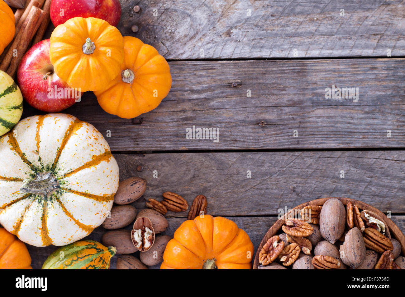 Pumpkins, nuts, indian corn and apples on a rustic table overhead ...