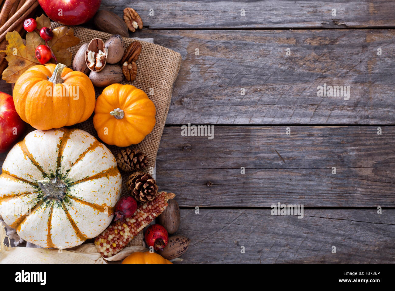 Pumpkins, nuts, indian corn and apples on a rustic table overhead ...