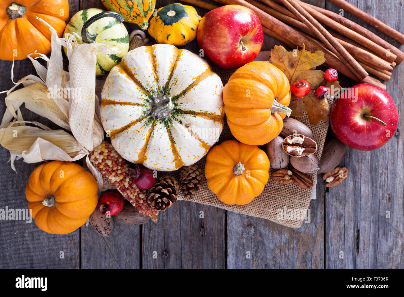 Pumpkins, nuts, indian corn and apples on a rustic table overhead ...