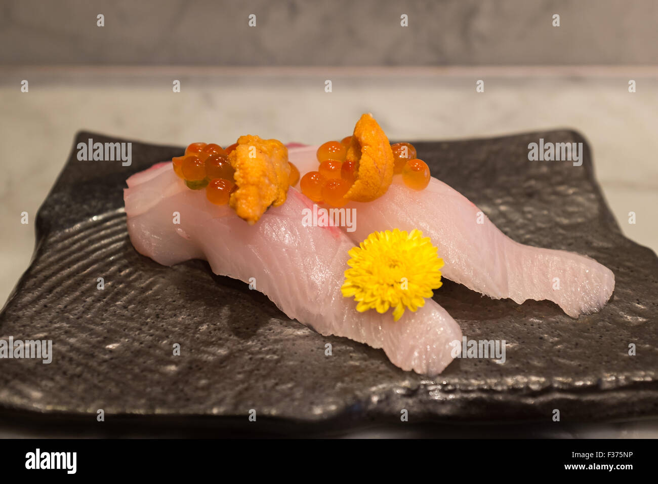 Kampachi sushi with Uni and Ikura on top on black ceramic plate Stock Photo
