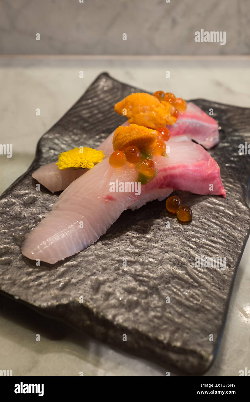 Kampachi sushi with Uni and Ikura on top on black ceramic plate Stock Photo