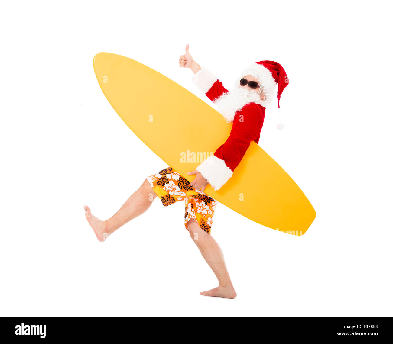 Happy Santa Claus holding surf board with thumb up Stock Photo