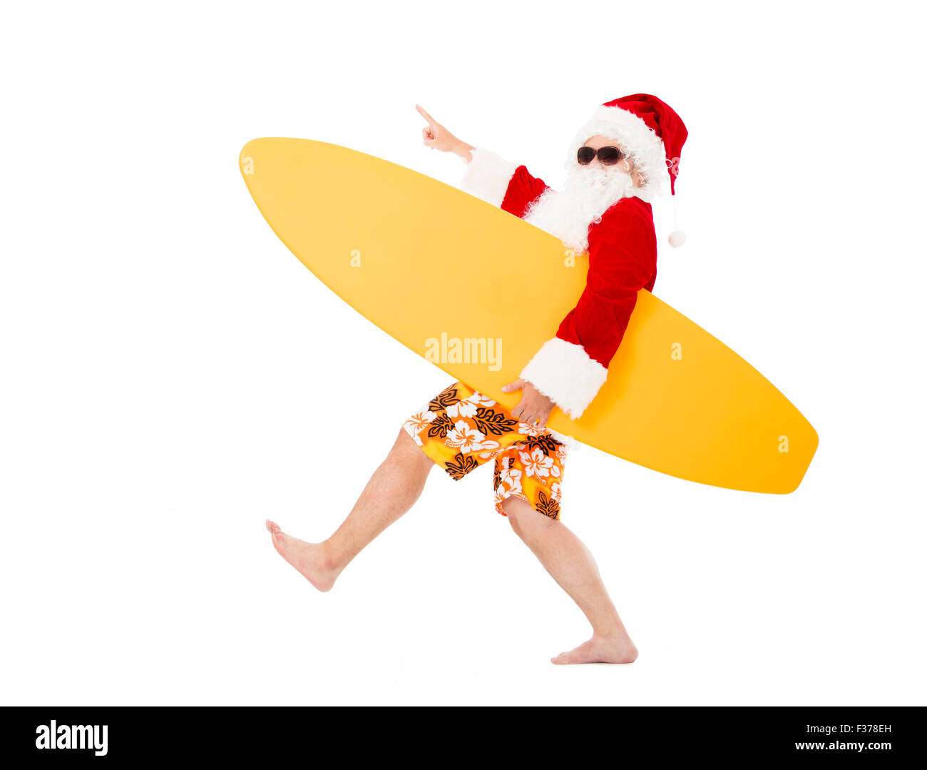 Happy Santa Claus holding surf board with pointing gesture Stock Photo