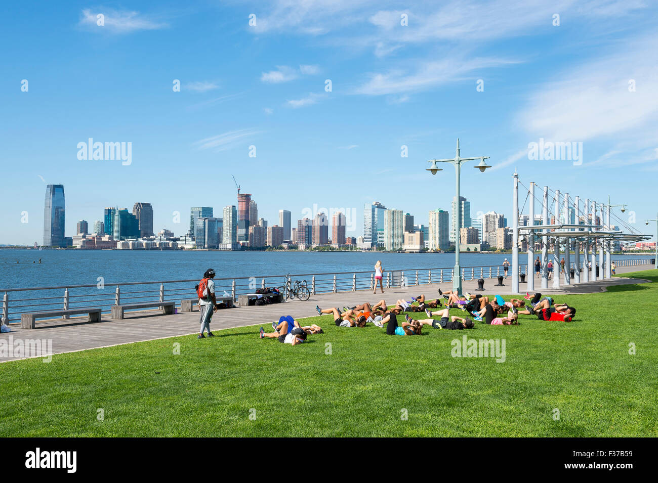 NEW YORK CITY, USA - AUGUST 29, 2015: Personal trainer leads group boot camp fitness class on the grass near the Hudson River. Stock Photo