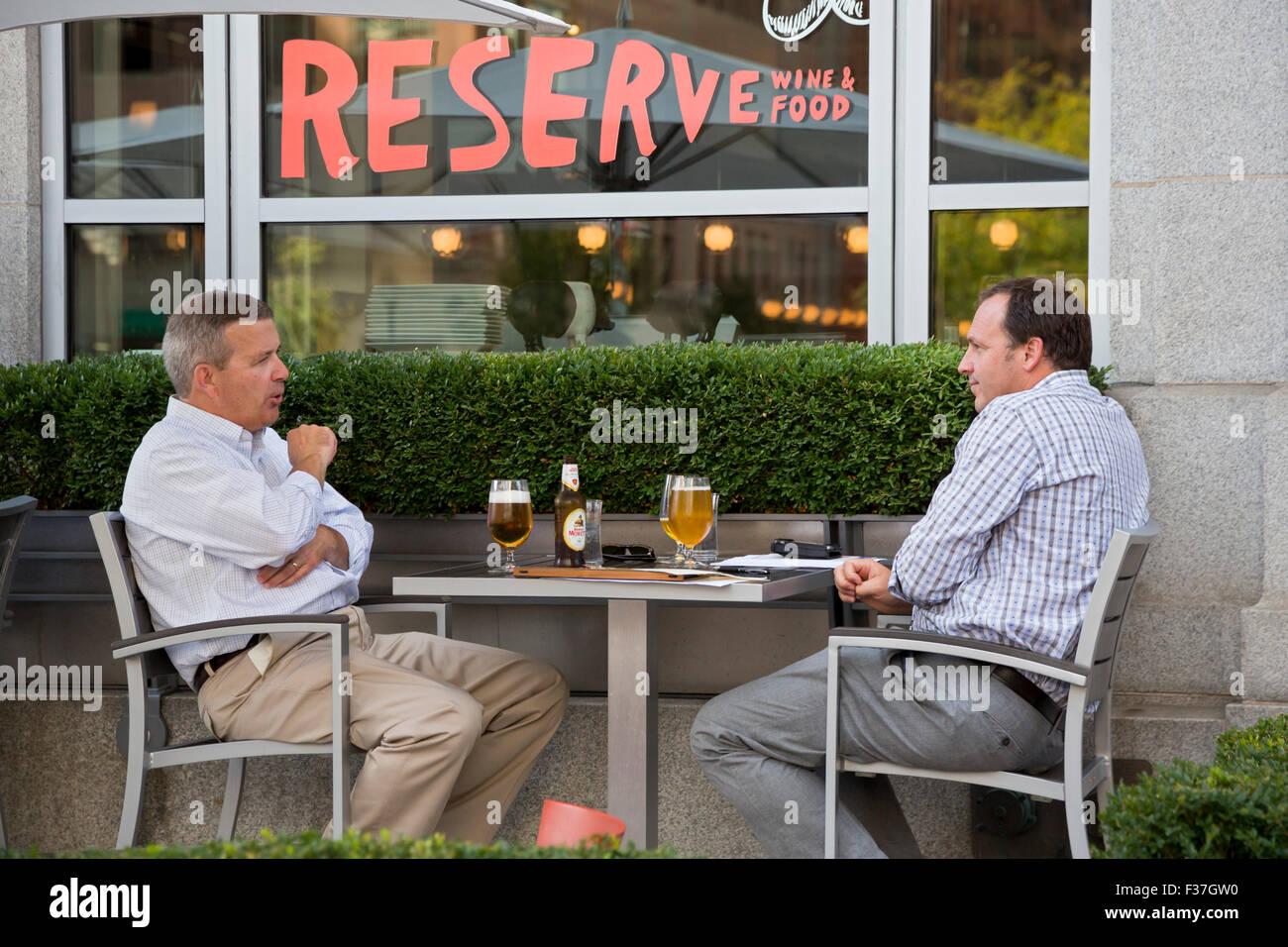 Grand Rapids, Michigan - Two men share beers at a restaurant's outside dining area. Grand Rapids has dozens of craft breweries. Stock Photo