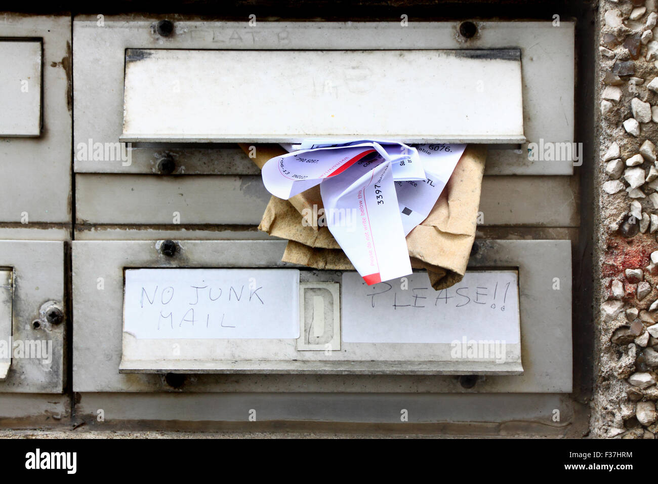 Junk mail stuffed into an apartment's mailbox, while another apartment owner has left instructions for no junk mail. Stock Photo