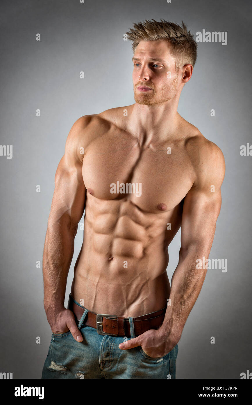 Blond Young Man With Well Trained Body Abs And Pecs And Wearing A Denim Trousers Look To The 