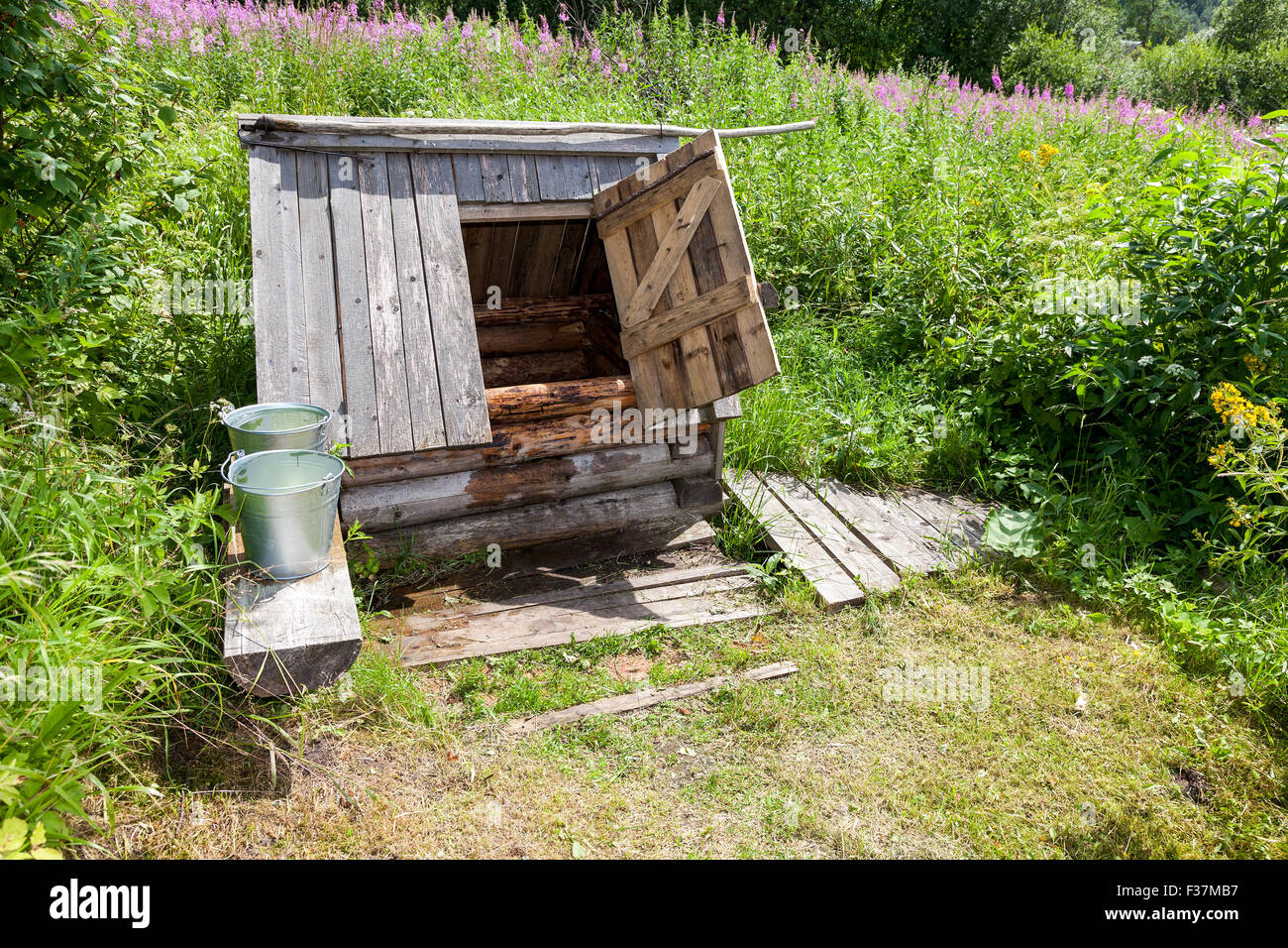 Village wooden water well with the open door and a buckets of water in