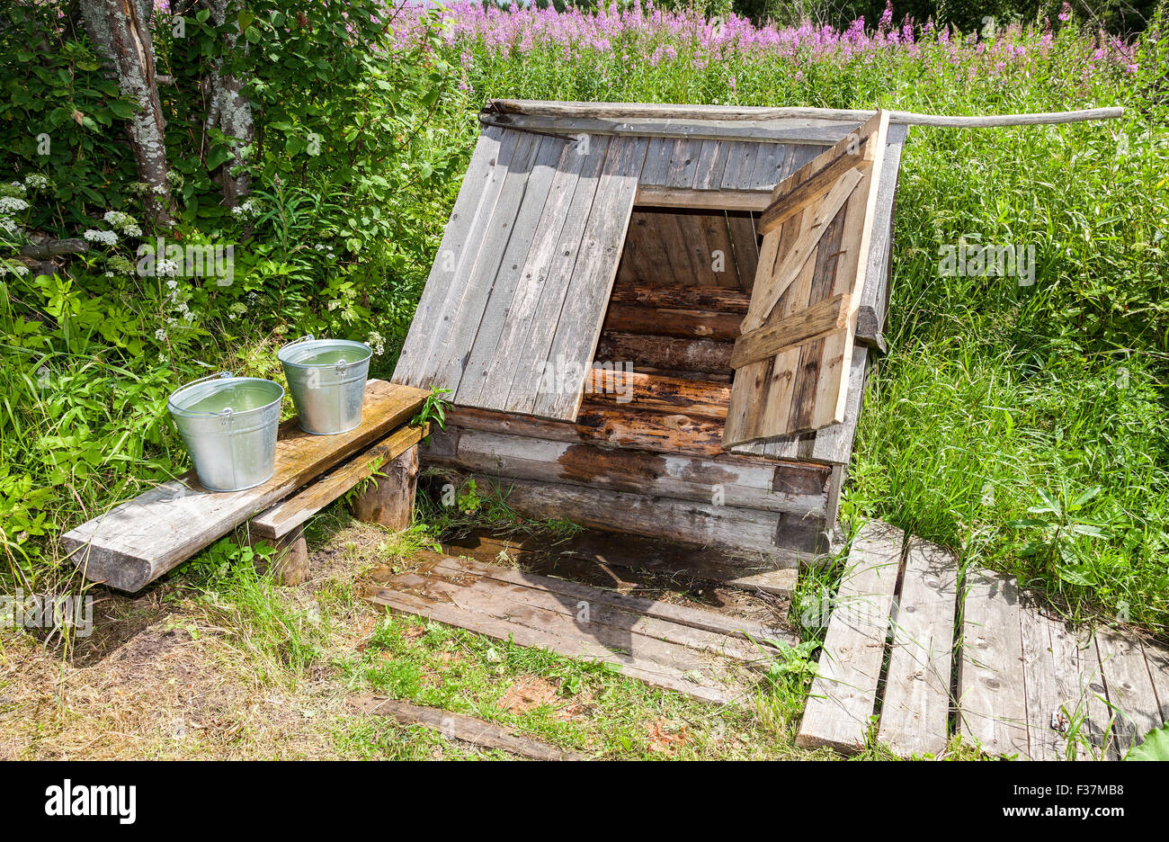 Village wooden water well with the open door and a buckets of water in