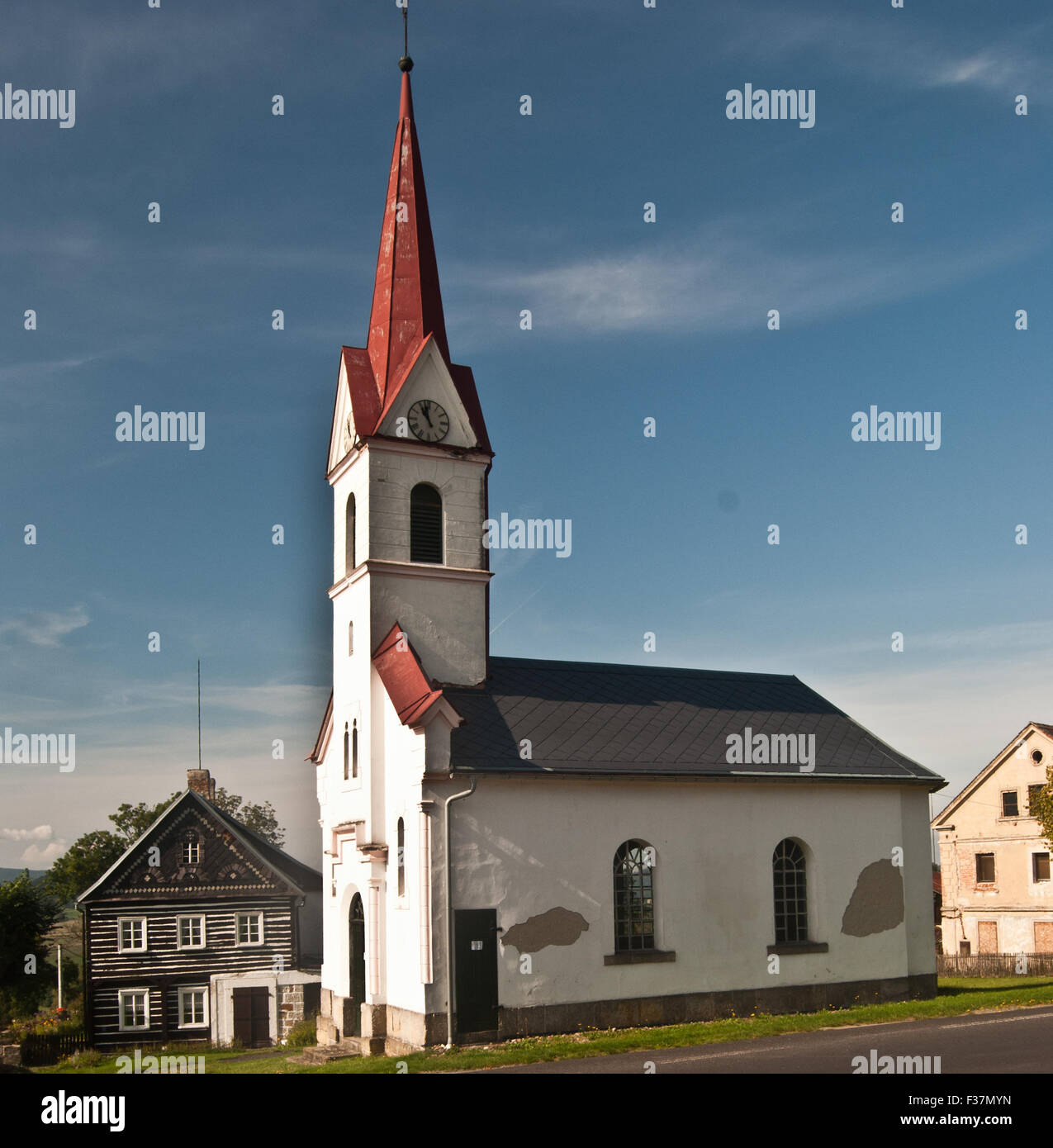 church with typical Sudetenland house in Svojkov village in North Bohemia with clear sky Stock Photo