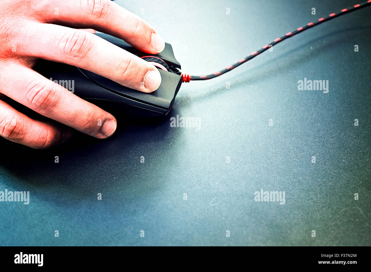 Male hand holding computer mouse on black surface. Computer technology conceptual image. Stock Photo