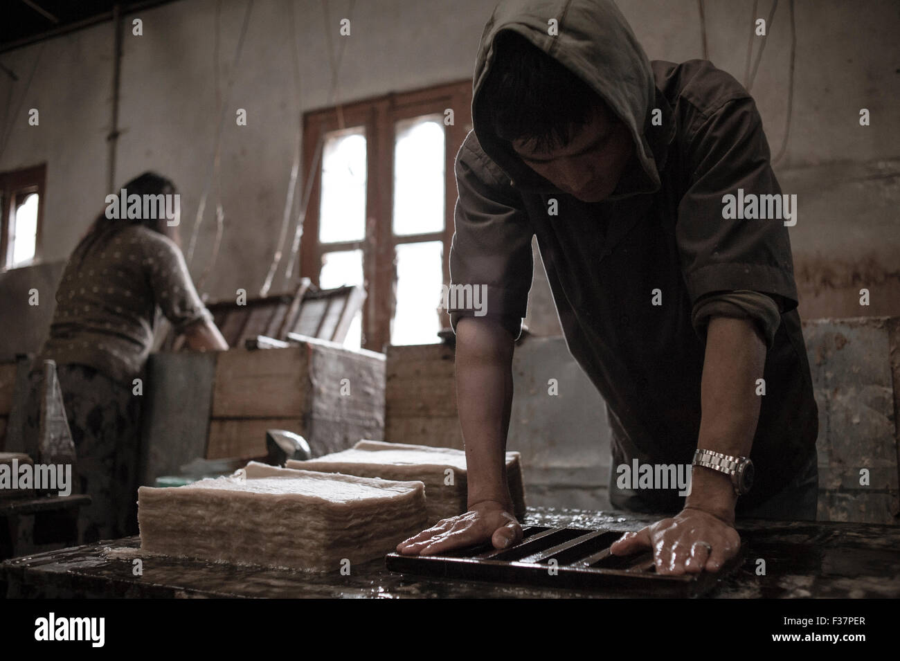 Jungshi Paper Factory, Thimphu, Bhutan. A man compresses handmade paper during the paper production process. The paper is purely handmade so sells at Stock Photo