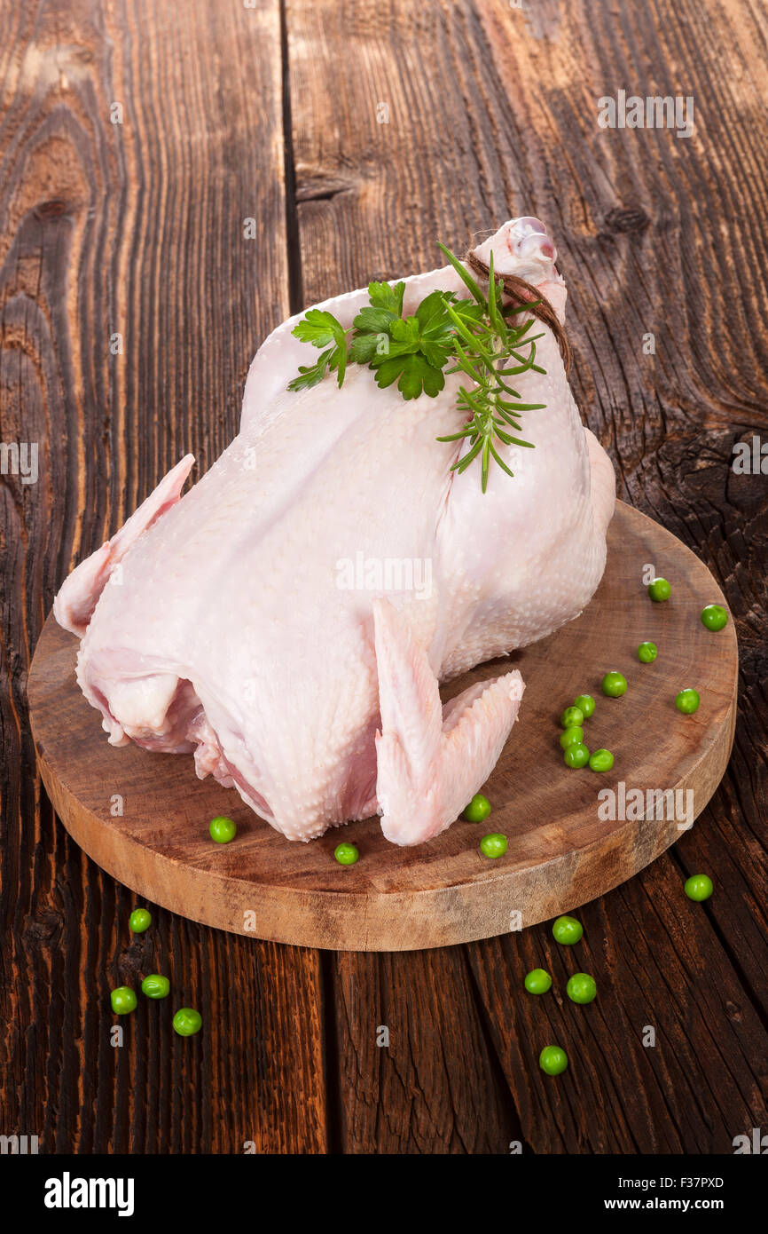 https://c8.alamy.com/comp/F37PXD/raw-whole-chicken-with-fresh-herbs-and-peas-on-brown-wooden-textured-F37PXD.jpg