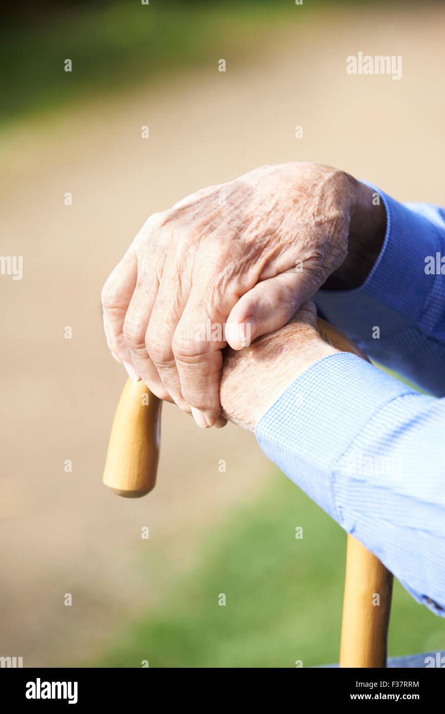Close Up Of Senior Man's Hands Resting On Walking Stick Stock Photo