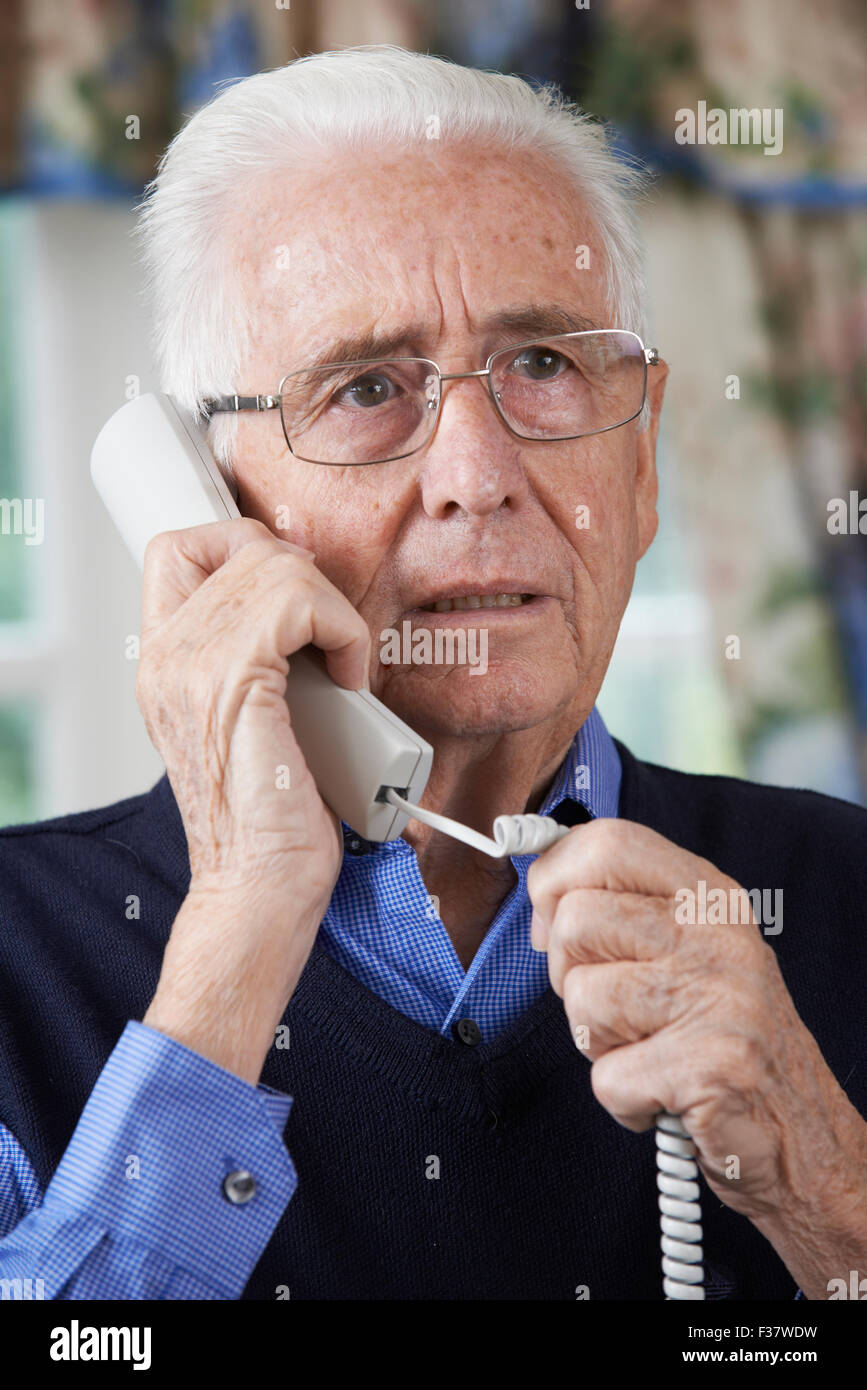 Worried Senior Man Answering Telephone At Home Stock Photo