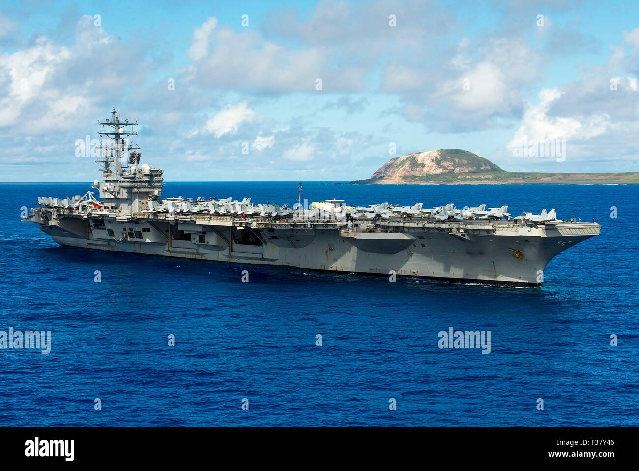 US Navy Nimitz-class nuclear aircraft carrier USS Ronald Reagan pauses to honor fallen service members from the Battle of Iwo Jima while underway off the island of Iwo To, formerly known as Iwo Jima September 29, 2015 in the Pacific Ocean.  This year marks the 70th anniversary of the end of World War II. Stock Photo
