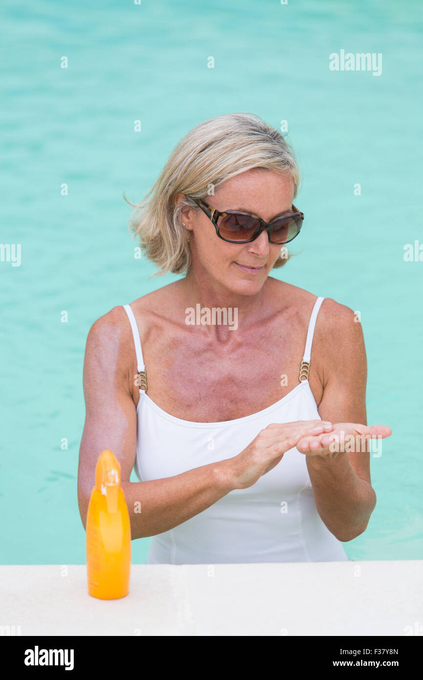 Woman applying sunblock at the beach. Stock Photo